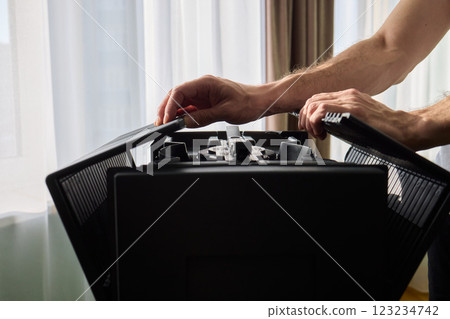 A person diligently assembling a contemporary black cooling device with precision and focus 123234742