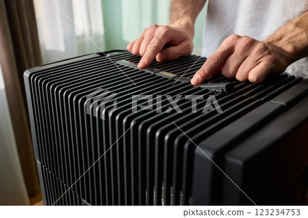 Hands adjusting a modern appliances control panel for optimal functionality and home comfort Hands adjusting a modern appliances control panel for optimal functionality and home comfort 123234753