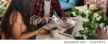 Banner wife and husband planning budget, checking finances, focused young woman using online calculator and counting bills or taxes, man using laptop, online banking services. Family sitting at table 123234831