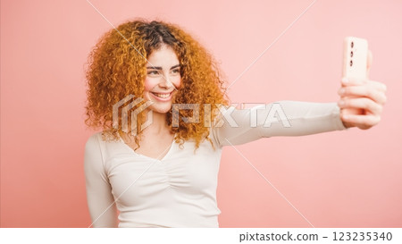 Young woman taking a selfie with smartphone on pink background Young woman taking a selfie with smartphone on pink background 123235340