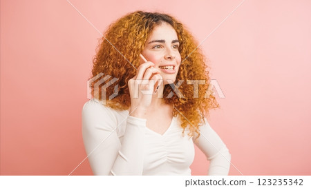 Young woman talking on smartphone with pink background Young woman talking on smartphone with pink background 123235342
