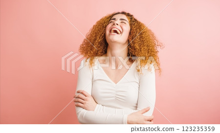 Redhead woman laughing with crossed arms on pink background Redhead woman laughing with crossed arms on pink background 123235359