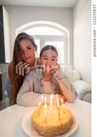 Birthday Cake Sisters Home Celebration: Two sisters celebrate a birthday with a lit cake indoors, capturing a joyful family moment. 123235637