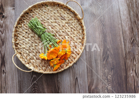 Fresh yellow marigold flower with green leaves on wicker tray and wooden background Fresh yellow marigold flower with green leaves on wicker tray and wooden background 123235986
