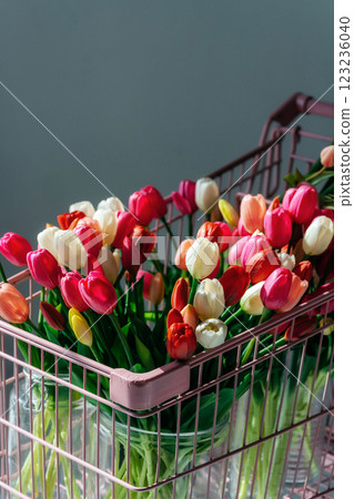 tulips in a pink supermarket trolley on a light background. bouquet of tulip buds in an iron basket tulips in a pink supermarket trolley on a light background. bouquet of tulip buds in an iron basket 123236040