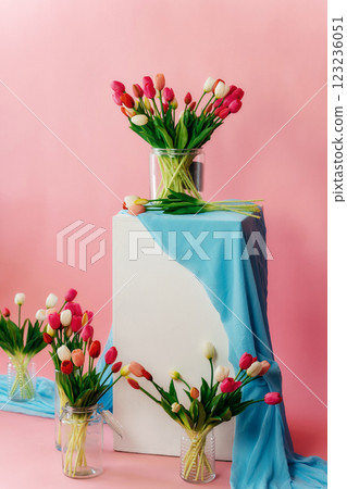 colored tulips with white stand on pink background. bouquet of tulip buds in glass vase on colored colored tulips with white stand on pink background. bouquet of tulip buds in glass vase on colored 123236051
