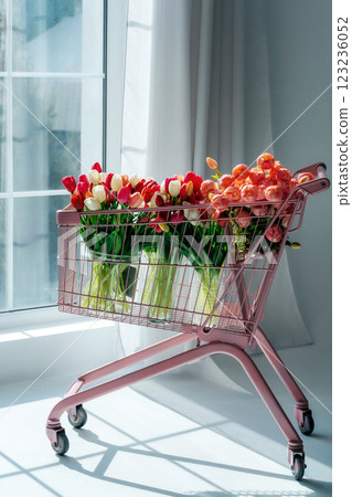 tulips in a pink supermarket trolley on a light background. bouquet of tulip buds in an iron basket tulips in a pink supermarket trolley on a light background. bouquet of tulip buds in an iron basket 123236052