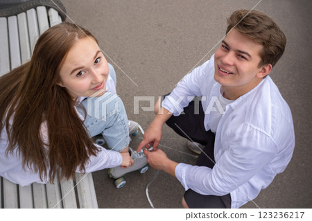 Young couple rollerblading and skateboarding in park. Happy and joyful girl and man doing sports together on warm summer day. High quality photo Young couple rollerblading and skateboarding in park. Happy and joyful girl and man doing sports together on warm summer day. High quality photo 123236217