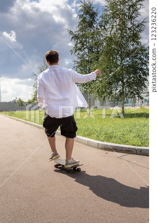 Young man in white shirt skateboarding in park. Vertical photo. High quality photo 123236220