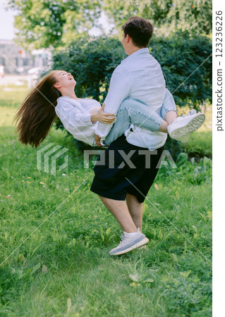 Loving couple of young girl and man are walking and having fun in park on warm summer day. Vertical photo. High quality photo 123236226