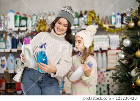 Woman with daughter choosing detergent and spray in decorated store Woman with daughter choosing detergent and spray in decorated store 123236420