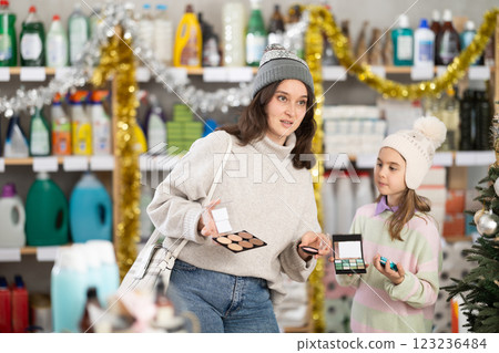 Woman with child family selects and studies label makeup cosmetic agent on New Year Eve 123236484