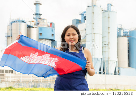 Happy young woman with flag of Cambodia against background of factory 123236538