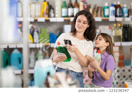 Woman and girl clients, by scanning QR code, gain access to information about dishwashing detergent Woman and girl clients, by scanning QR code, gain access to information about dishwashing detergent 123236547