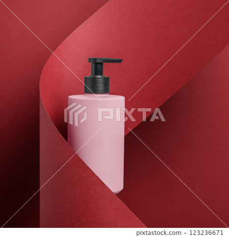 A stylish pink pump bottle displayed against a bold red background, creating eyecatching appeal A stylish pink pump bottle displayed against a bold red background, creating eyecatching appeal 123236671