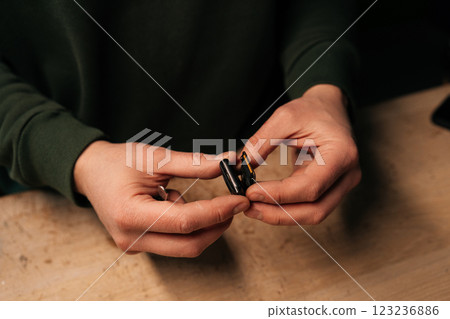 Closeup hands of unrecognizable technician male carefully opening smartwatch to replace battery, demonstrating intricate process of device repair. Concept of process electronic device maintenance. 123236886