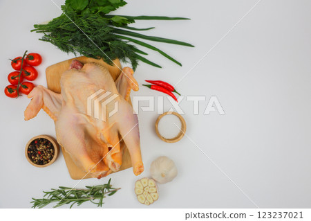 A raw processed chicken carcass lies on a wooden board with spices in wooden bowls, herbs, herbs and vegetables with space for text on a white background. The concept of cooking, wholesome and healthy A raw processed chicken carcass lies on a wooden board with spices in wooden bowls, herbs, herbs and vegetables with space for text on a white background. The concept of cooking, wholesome and healthy 123237021