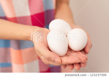 Image of a woman holding a raw egg (stock photo) Image of a woman holding a raw egg (stock photo) 123237300