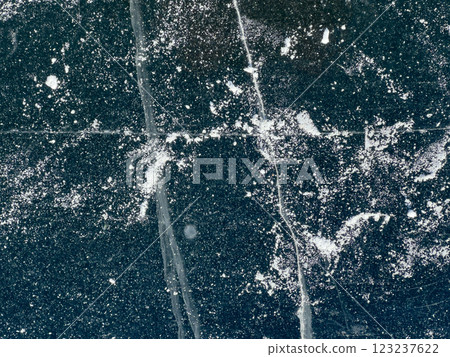 A top-down view of a frozen surface with visible cracks and a light dusting of snow, capturing the intricate details and natural patterns of the ice. A top-down view of a frozen surface with visible cracks and a light dusting of snow, capturing the intricate details and natural patterns of the ice. 123237622