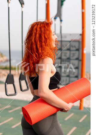 Redheaded jogger woman holding rolled up exercise 123239172