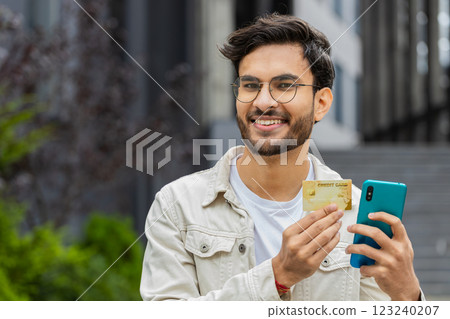 Indian man using credit bank card smartphone while transferring money, purchases online shopping Indian man using credit bank card smartphone while transferring money, purchases online shopping 123240207
