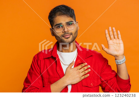 Indian man raising hand to take oath, promising to be honest and to tell truth keeping hand on chest Indian man raising hand to take oath, promising to be honest and to tell truth keeping hand on chest 123240238