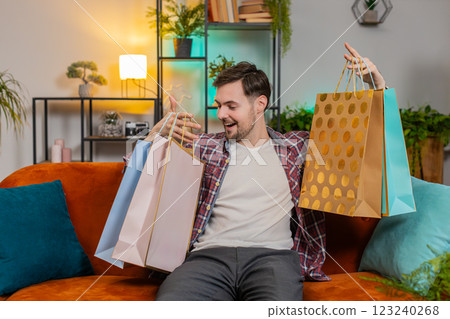 Young happy man shopaholic consumer came back home after shopping sale with purchase bags orders 123240268