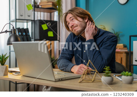 Business man freelancer overworking suffers from spine neck muscle pain at home office workplace Business man freelancer overworking suffers from spine neck muscle pain at home office workplace 123240309