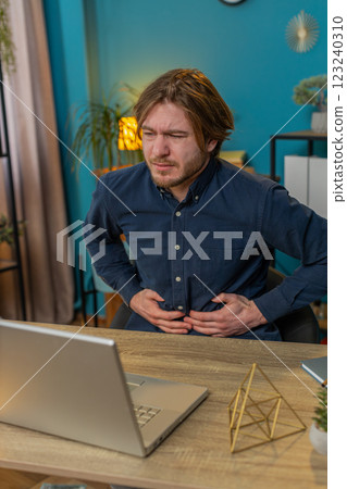 Upset businessman feeling stomach ache overeating during work process on laptop in home office Upset businessman feeling stomach ache overeating during work process on laptop in home office 123240310