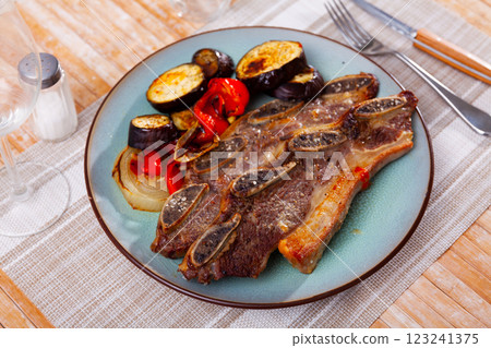 on blue plate-grilled beef ribs with fried vegetables-aubergine, pepper,onion.Spanish dish-churrasco on blue plate-grilled beef ribs with fried vegetables-aubergine, pepper,onion.Spanish dish-churrasco 123241375