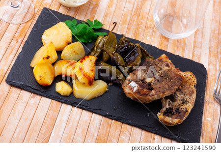 Fried lamb leg steaks with potatoes and padron peppers on slate board 123241590