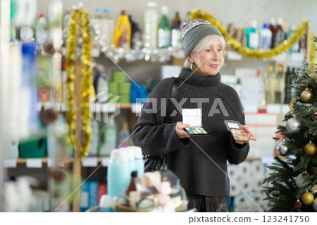 Elderly woman chooses cosmetics in decorated household chemicals store Elderly woman chooses cosmetics in decorated household chemicals store 123241750