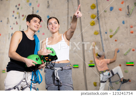 fitness instructors in gym discuss alpinist practice artificial rock climbing wall 123241754