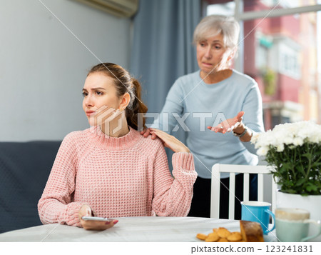 Offended young woman listening to reproaches from mother at table Offended young woman listening to reproaches from mother at table 123241831