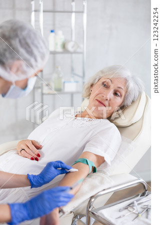 Female doctor doing injection to sleepy tired old woman in clinic. 123242254