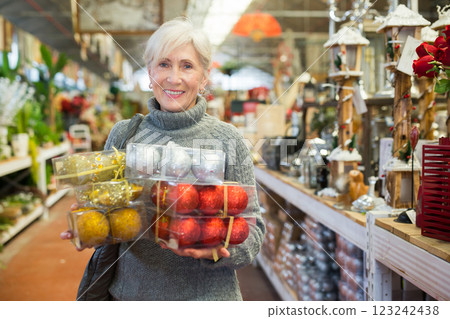 Elderly woman with package of christmas baubles in shop 123242438