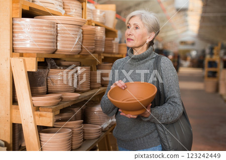 Aged woman choosing earthenware crockery in store 123242449