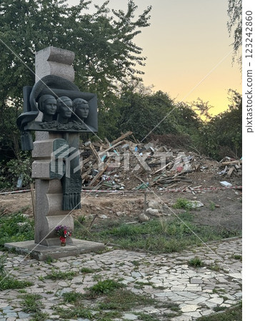 War memorial monument with three faces near demolition site at sunset War memorial monument with three faces near demolition site at sunset 123242860
