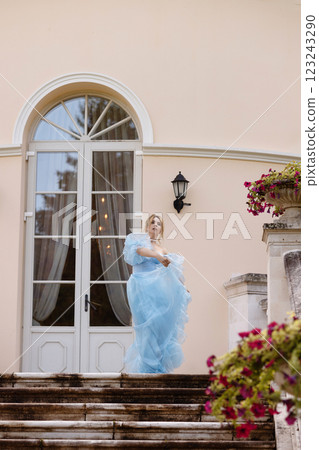Elegant Woman in a Flowing Blue Gown Walking Down the old stone Stairs 123243290