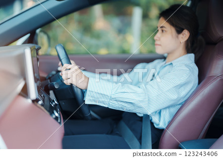 Businesswoman driver driving a car on the road, hand controlling steering wheel in electric modern automobile. Journey, trip and safety Transportation concepts 123243406
