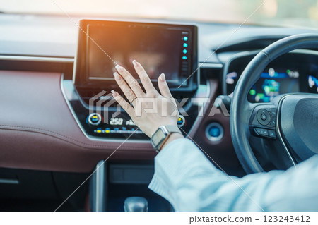 Woman hand adjusting temperature the air flowing during driving car on the road, air conditioner cooling system inside the car. Adjust, temperature and transport concept 123243412