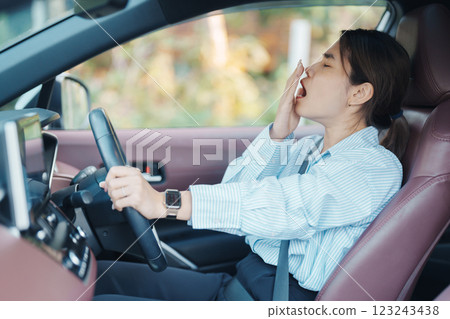 woman feeling sleepy and yawn during drive car long time. Asian girl tired and fatigue having headache after driving car in traffic jam. Sleep, stretching and safety concept 123243438