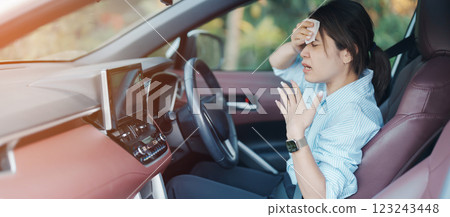 woman driving car with broken air conditioner in hot summer weather, uses tissue paper napkin to wipe the sweat off her forehead. Businesswoman driver is tired, Exhausted overheated and stressed 123243448