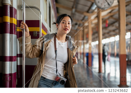 Asian woman carrying a camera is looking around while coming down from the carriage at train station 123243682