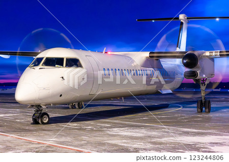 Close-up of a white passenger turboprop aircraft taxis through an airport at dusk 123244806