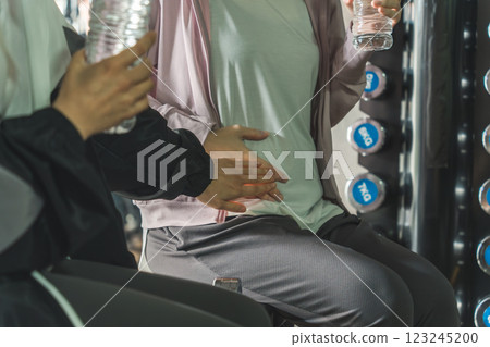 A woman talking to a pregnant woman who is exercising, stretching, and doing maternity training at the gym during pregnancy A woman talking to a pregnant woman who is exercising, stretching, and doing maternity training at the gym during pregnancy 123245200