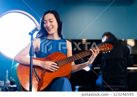 Men and women jamming on stage with guitar and piano Men and women jamming on stage with guitar and piano 123246545