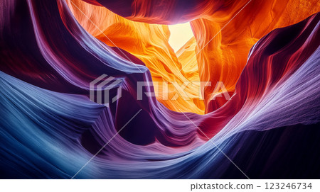 Abstract sand formations of a canyon. The stone walls curve and wind, lit by sunlight in shades of orange, purple, and blue. 123246734