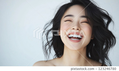 Close-up portrait of an Asian woman laughing joyfully with radiant skin, perfectly styled hair, and sparkling white teeth. Bright, cheerful. Close-up portrait of an Asian woman laughing joyfully with radiant skin, perfectly styled hair, and sparkling white teeth. Bright, cheerful. 123246780