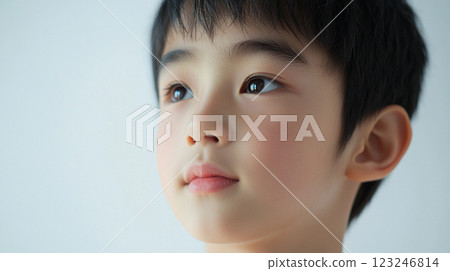A contemplative portrait of a young child, looking upwards with soft light highlighting delicate facial features against a pale backdrop. A contemplative portrait of a young child, looking upwards with soft light highlighting delicate facial features against a pale backdrop. 123246814